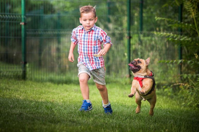 A child running beside a small dog outdoors