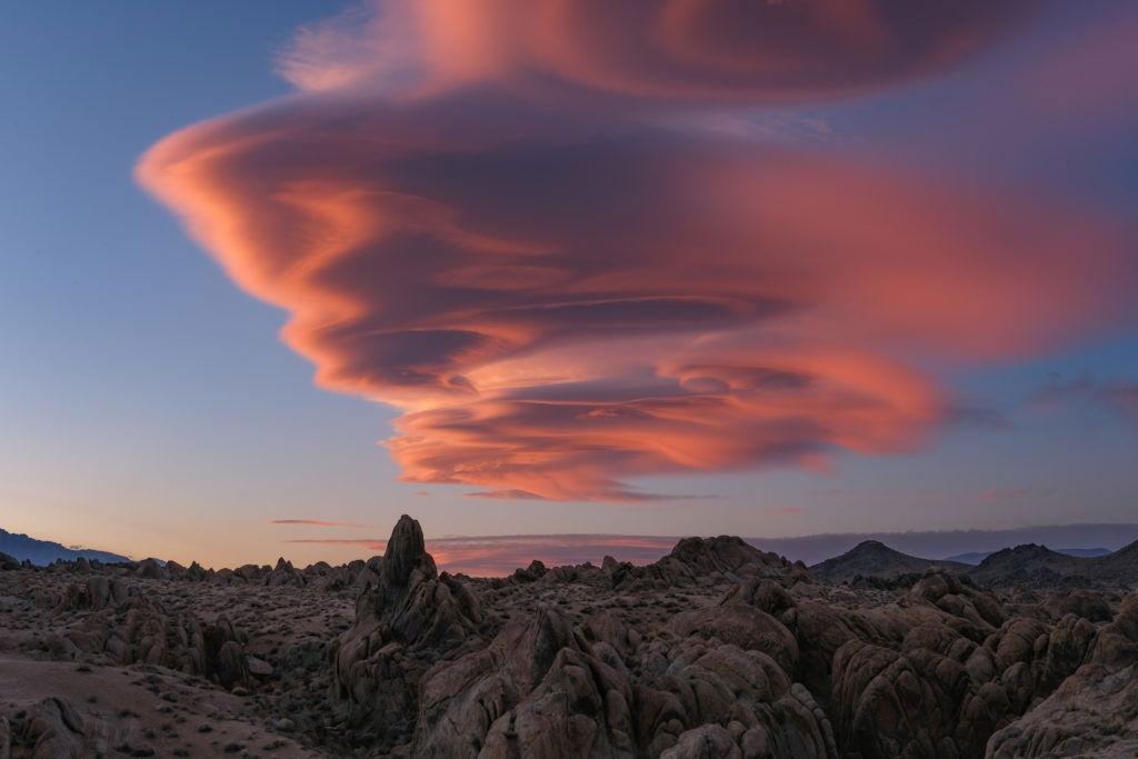 A dramatic lenticular cloud glowing above a rocky landscape